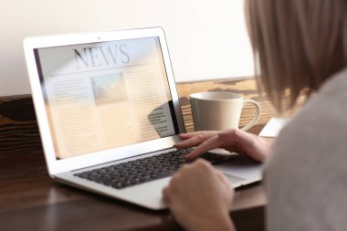 Olgun kadın haber kafede dizüstü bilgisayar ekranında okuma