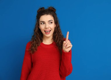 Renk arka plan üzerinde yükseltilmiş işaret parmağı ile güzel genç kadın portresi