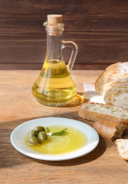 Zeytinyağı ve ahşap masa üzerinde taze ekmek ile plaka