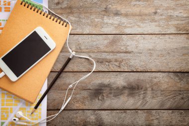 Dizüstü bilgisayar, cep telefonu ve harita üzerinde ahşap arka plan. Seyahat kavramı