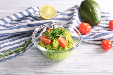 Taze guacamole ve ahşap masa üzerinde domates ile kase