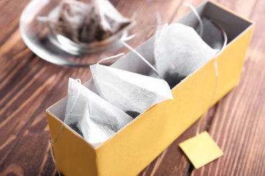 Ahşap masa üzerinde çay poşetleri ile kutu