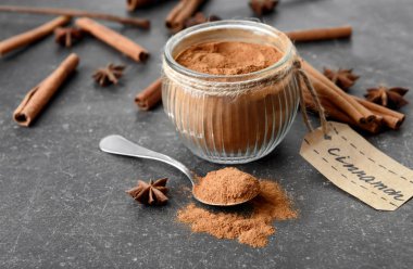 Kase ve gri arka plan üzerinde toz tarçın kaşıkla