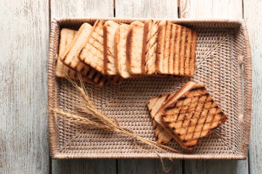 Hasır tepsi ahşap masa üzerinde kızarmış ekmek ile