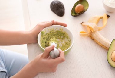 Kadın mutfakta avokado ile besleyici maske yapma