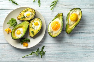 Ahşap masa üzerinde yumurta ile pişmiş avokado