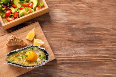 Yumurta ve ahşap arka plan üzerinde sebze pişmiş avokado