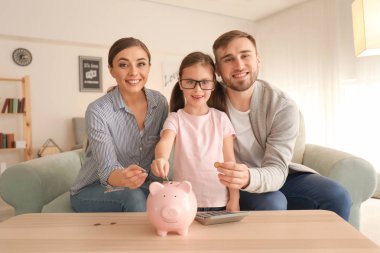 Mutlu küçük kız ailesiyle koyarak piggy banka kapalı bozuk paralar. Para tasarruf kavramı