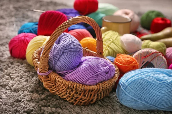 Wicker basket with knitting yarn on carpet