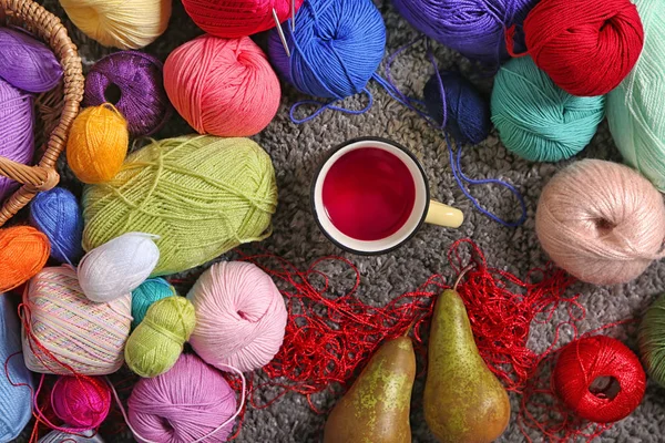 Colorful knitting yarn with metal cup of tea on carpet