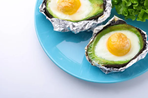 Baked avocado with eggs on white background