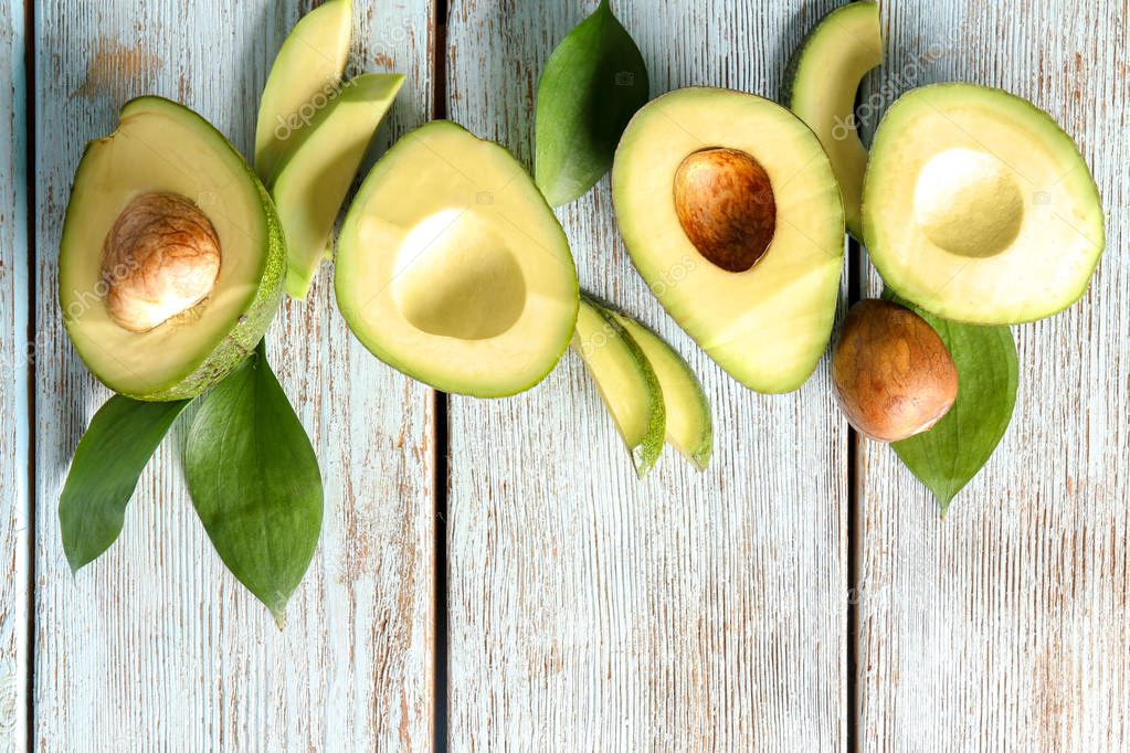 Composition with ripe avocados on light wooden background