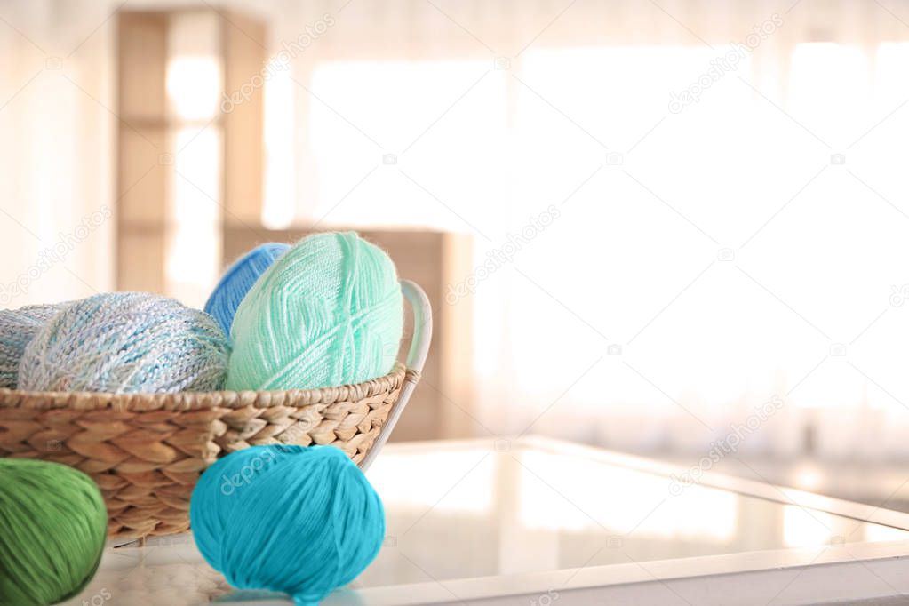 Wicker basket with knitting yarn on glass table