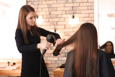 Profesyonel kuaför müşteriyle kuaförde çalışıyor.