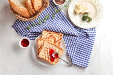 Tost ekmeğine reçel ve tablo üzerine tereyağı