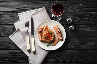 Lezzetli ızgara biftek ve masada kırmızı şarap ile plaka