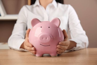 Masasında kumbarası olan kadın.