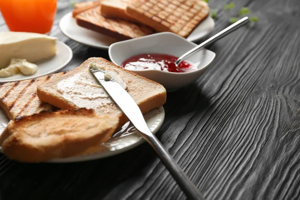 Toasted bread with butter and jam on wooden table