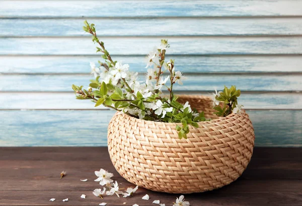 Wicker box with blossoming branches on wooden table