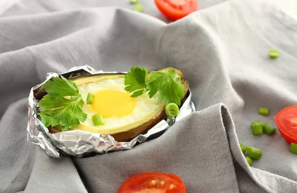 Avocado baked with egg in foil on table