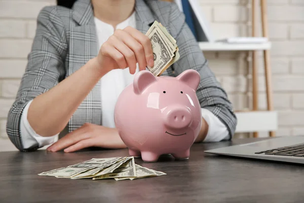 Vrouw Geld Steken Piggy Bank Tafel — Stockfoto