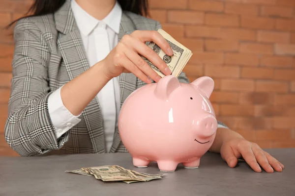 Vrouw Geld Steken Piggy Bank Tafel — Stockfoto