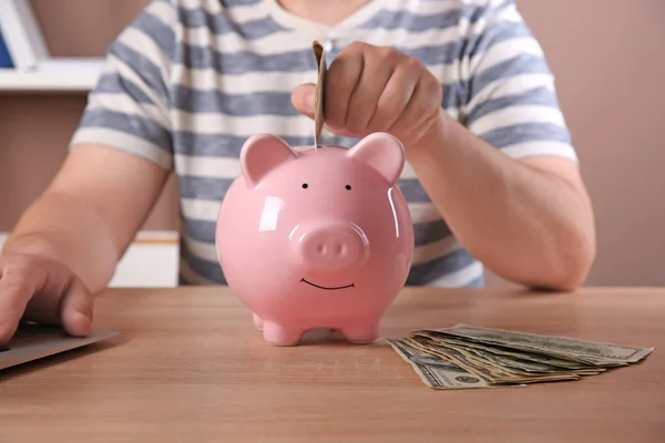 Man Putting Money Piggy Bank Table — Stock Photo, Image