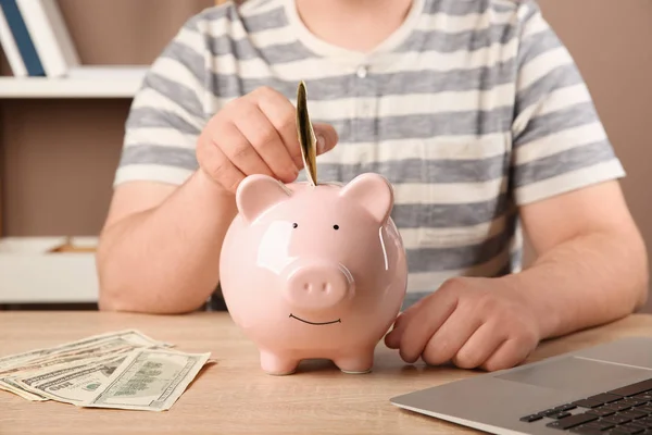 Man Putting Money Piggy Bank Table — Stock Photo, Image