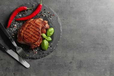 Lezzetli ızgara biftek ve gri arka plan üzerine baharat ile kayrak plaka