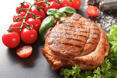 Gri arka plan üzerinde sebze ile lezzetli ızgara biftek