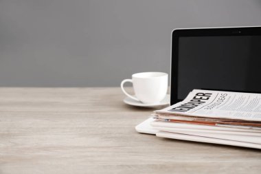 Gazeteler, dizüstü bilgisayar ve ahşap masa üzerinde kahve yığını