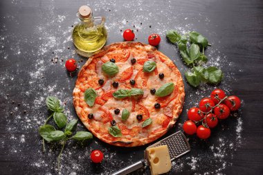 Koyu arka plan üzerinde malzemelerle lezzetli pizza