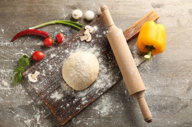 Çiğ hamur ve malzemeler ahşap arka plan üzerinde pizza ile kompozisyon