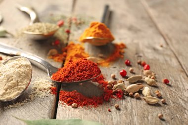 Ahşap masa üzerinde farklı baharatlar ile metal kaşık