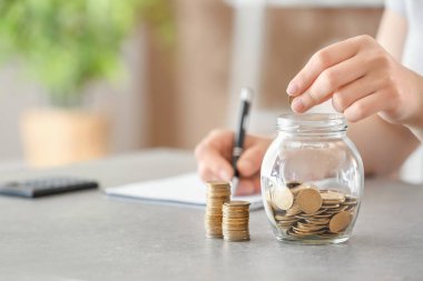 Paralar cam kavanozun içine masanın üzerine koyarak kadın. Tasarruf kavramı