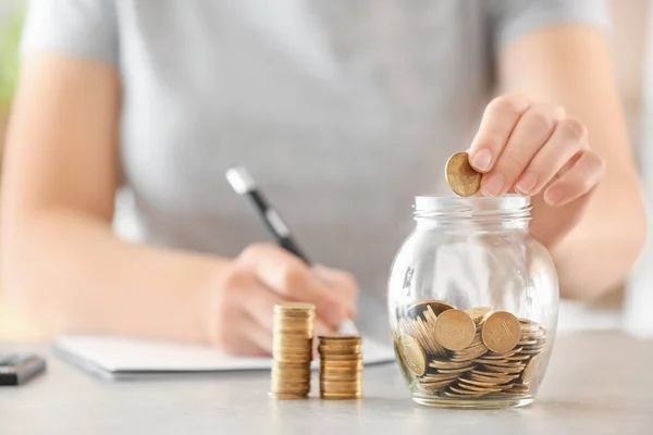 Woman Putting Coins Glass Jar Table Savings Concept — Stock Photo, Image