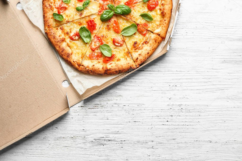 Carton box with delicious pizza Margherita on wooden background