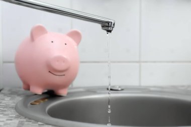 Kumbara ve üzerinden dökülen su dokunun. Su tasarrufu kavramı