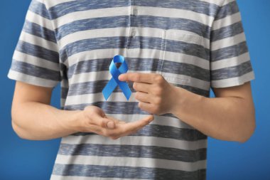 Mavi kurdele renk arka planda, closeup tutan adam. Prostat kanseri kavramı