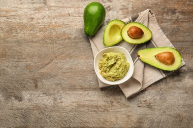 Lezzetli guacamole ve ahşap masa üzerinde olgunlaşmış avokado ile kase
