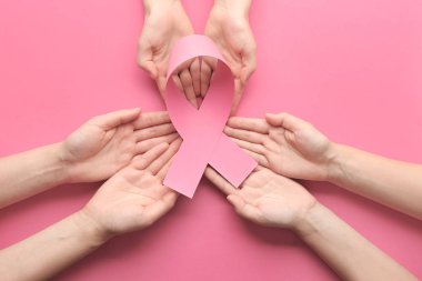 Pembe kurdele renk arka plan üzerinde tutan eller. Meme kanseri bilinçlendirme kavramı