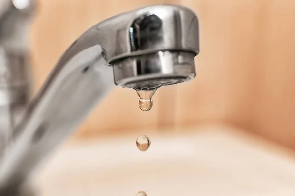 Metal tap with dripping water, closeup. Water saving concept