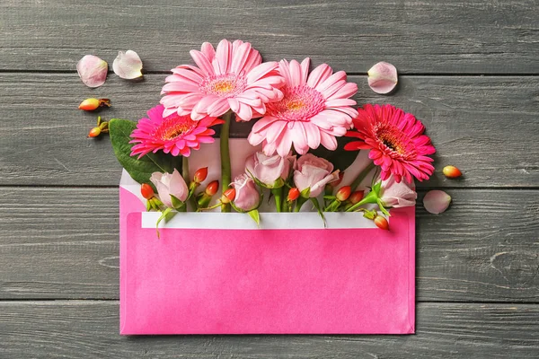 Open mail envelope with flowers on wooden background