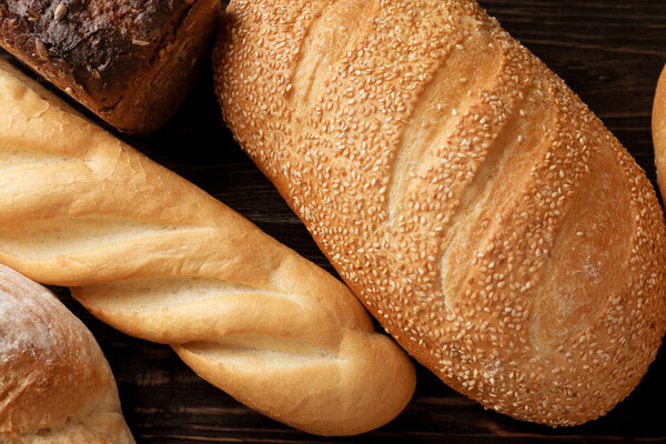 Variety of fresh tasty bread on wooden background