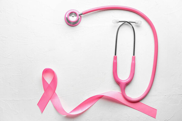 Pink ribbon and stethoscope on light background. Breast cancer awareness concept