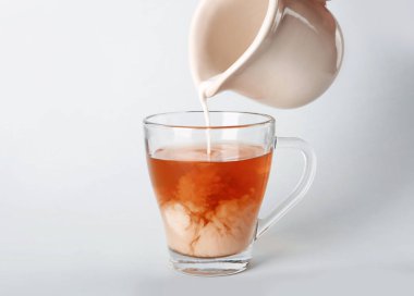 Açık renkli cam fincan çay ile içine süt dökme