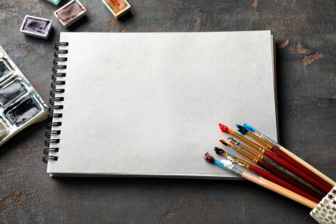 Defter ile gri arka plan üzerinde boya fırçaları