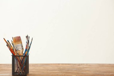 Boya fırçaları karşı açık renkli ahşap tablo ile sahibi