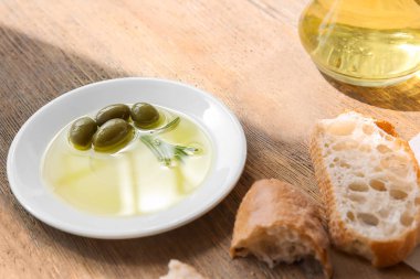 Zeytinyağı ve ahşap masa üzerinde taze ekmek ile plaka