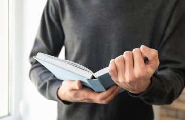 Adam closeup evde, ilginç bir kitap okuma